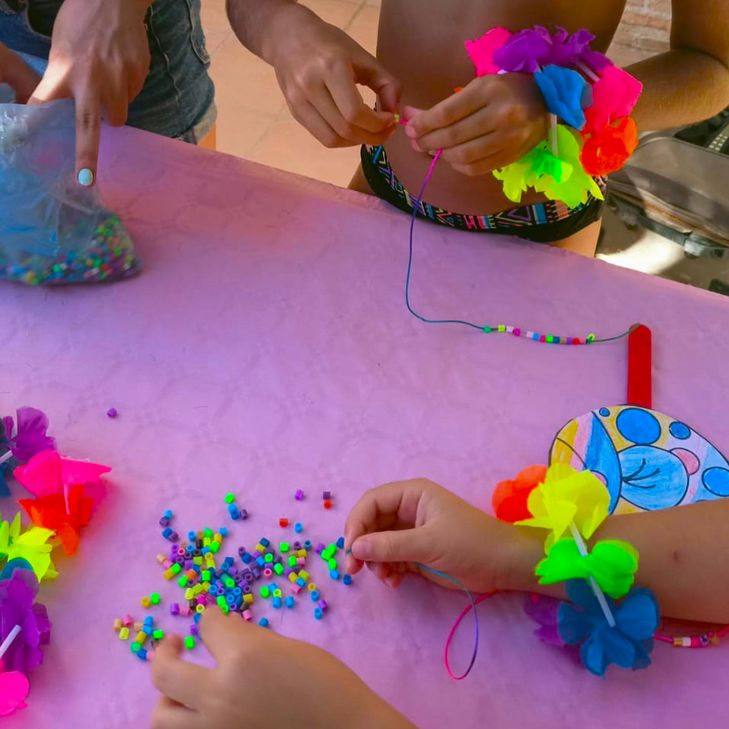 Los Cuentos De Alba niños haciendo collares de bolas en mesa violeta